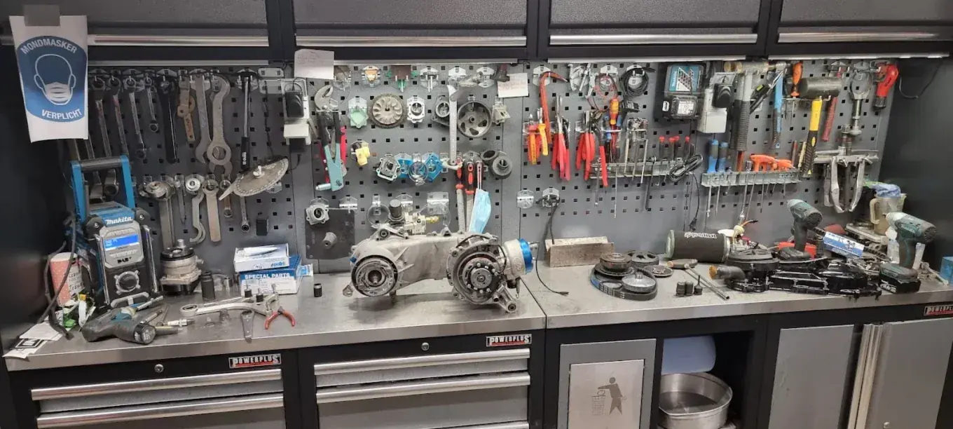 Werkbank met een gedemonteerd scootermotorblok bij Thunder Racing
